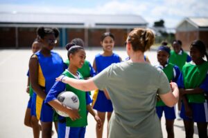 Coach talking to netball teams with hand on shoulder of team captain